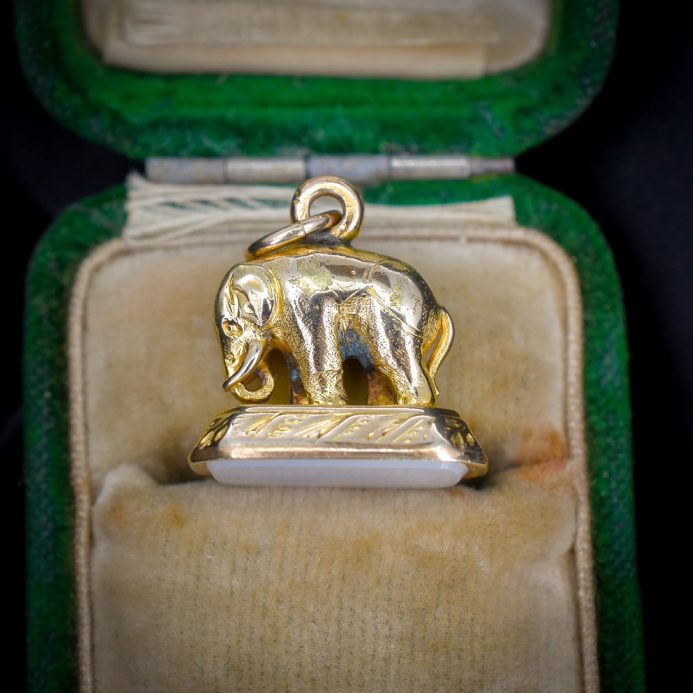 An antique gold-cased fob seal featuring a sculpted elephant figure mounted on a patterned base with a flat chalcedony matrix. View VI