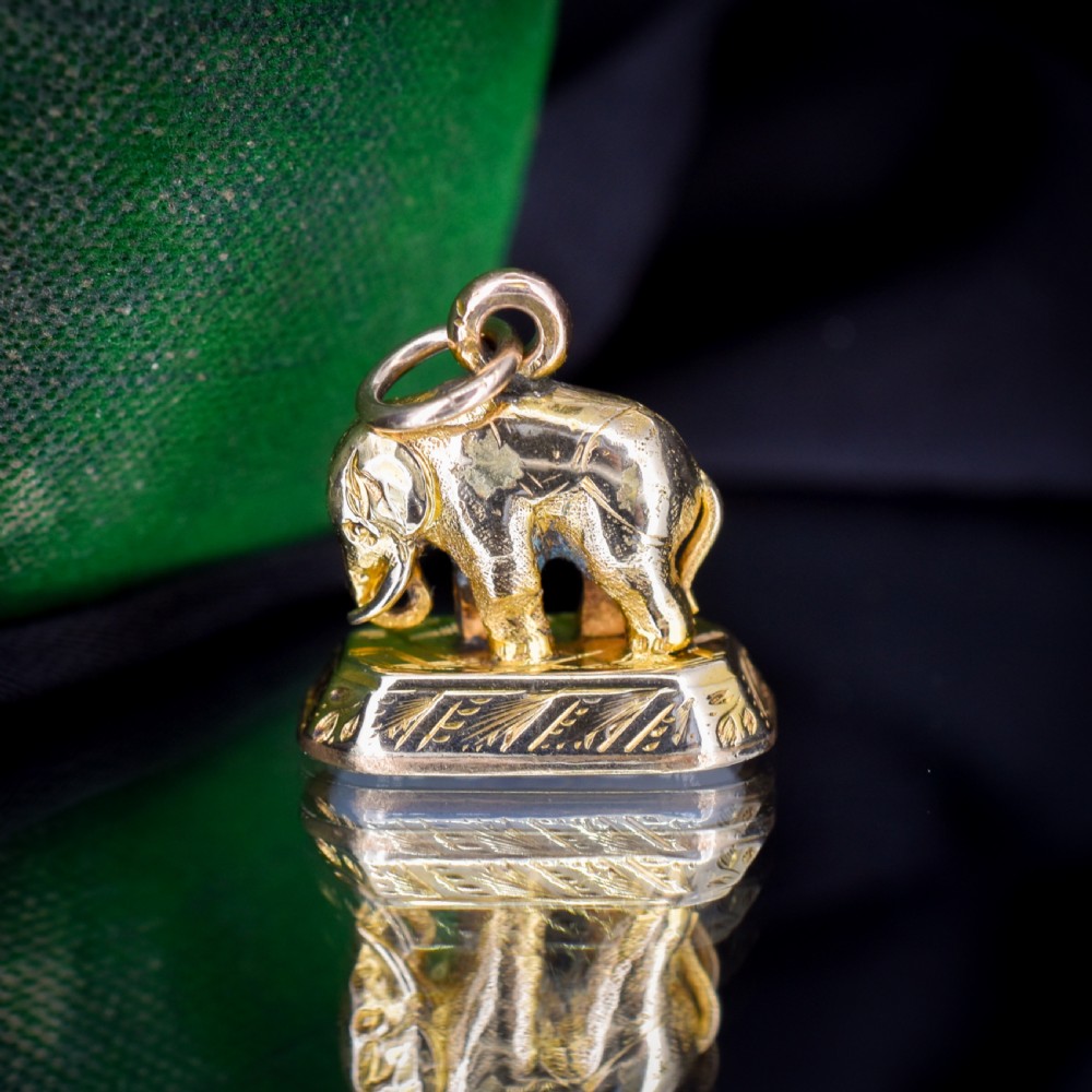 An antique gold-cased fob seal featuring a sculpted elephant figure mounted on a patterned base with a flat chalcedony matrix. View IX