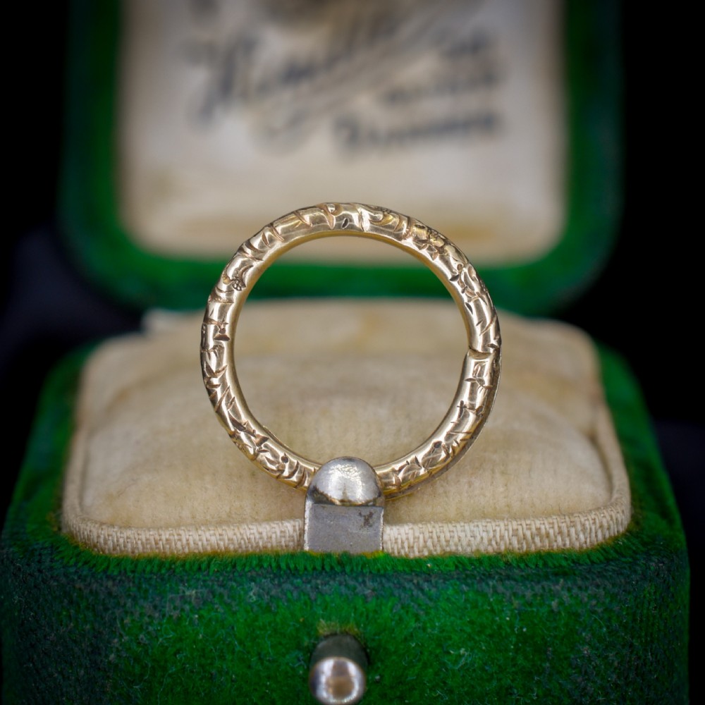 A small circular 12ct yellow gold split ring decorated with hand-engraved patterns along its outer edge.