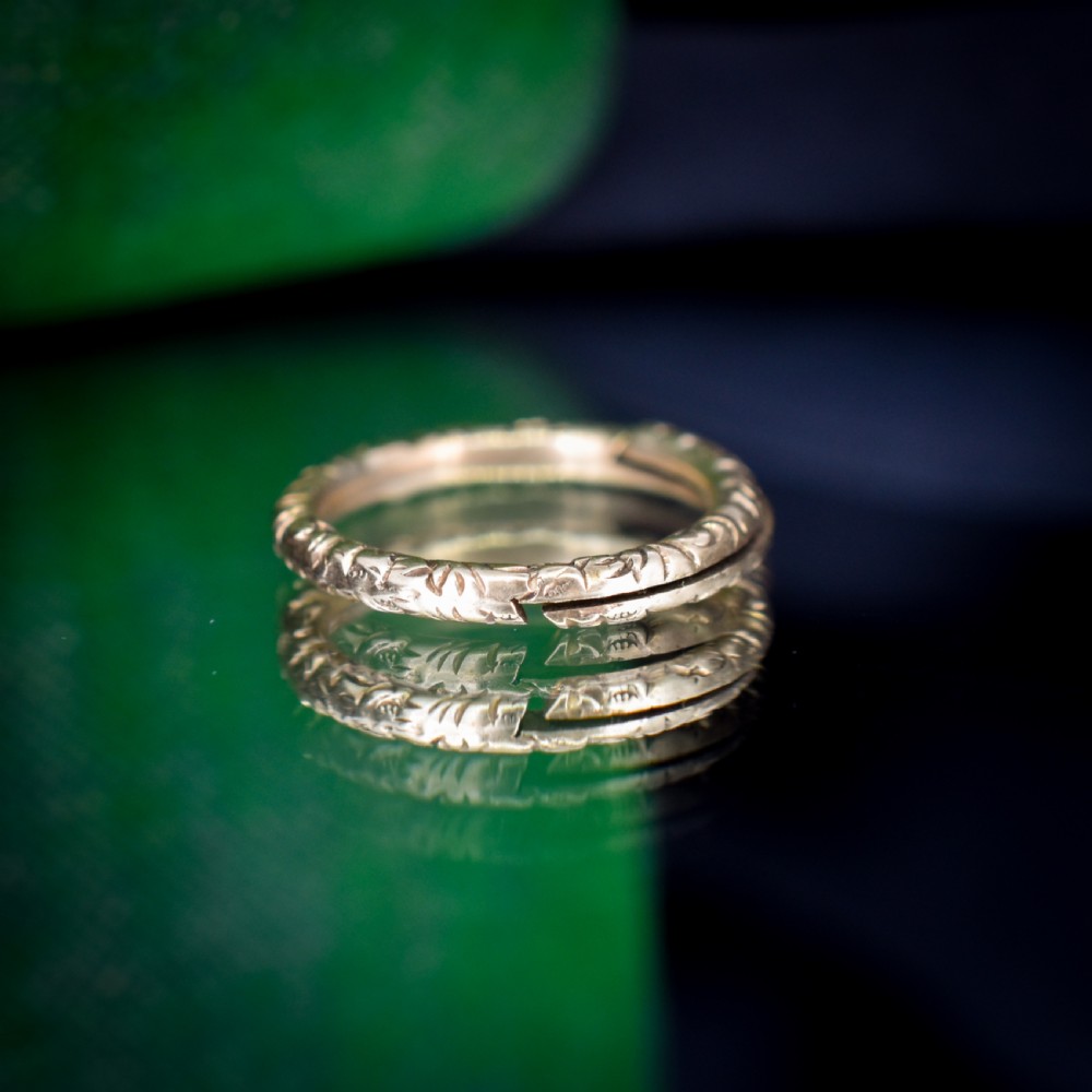 A small circular 12ct yellow gold split ring decorated with hand-engraved patterns along its outer edge. View VI