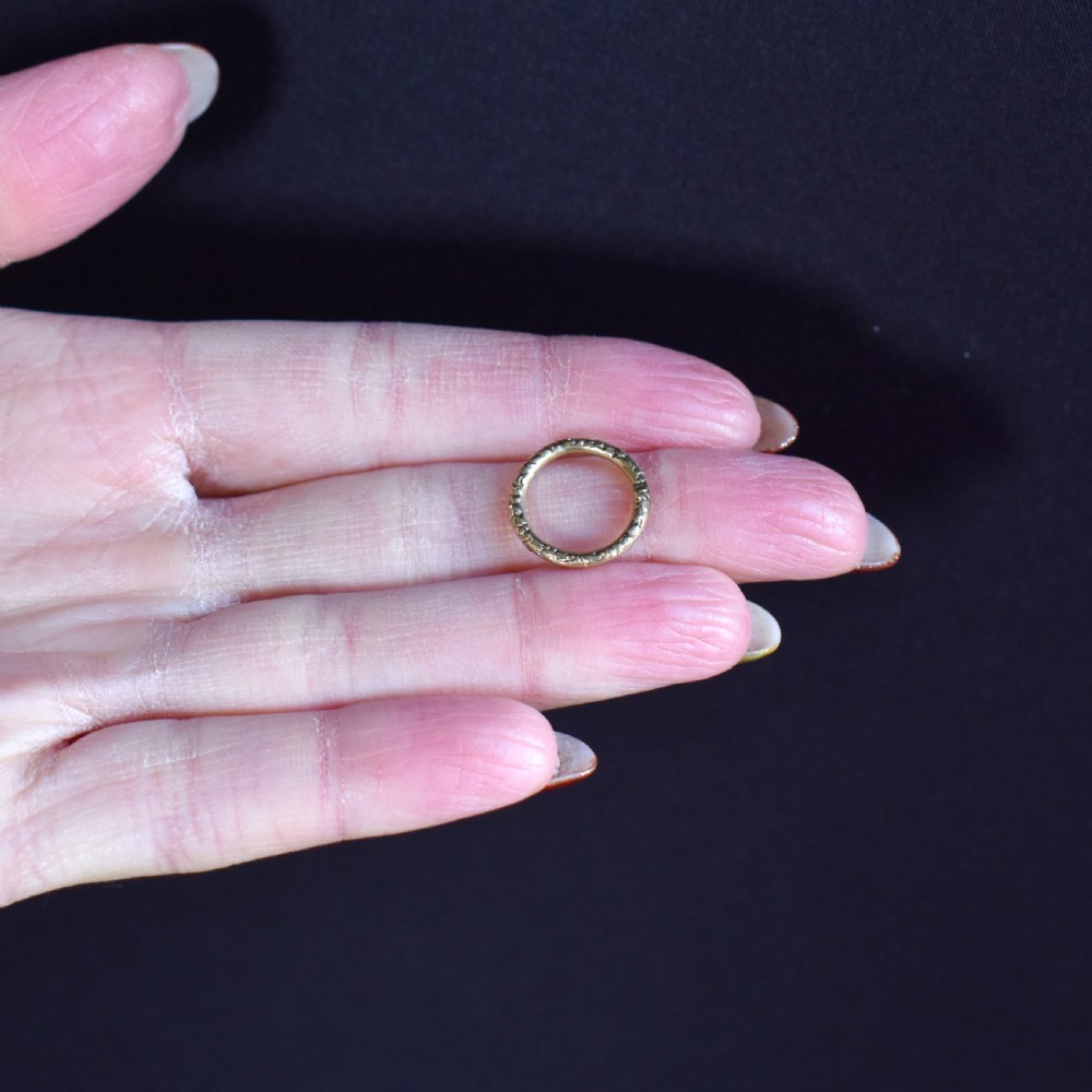 A small circular 12ct yellow gold split ring decorated with hand-engraved patterns along its outer edge. View VII