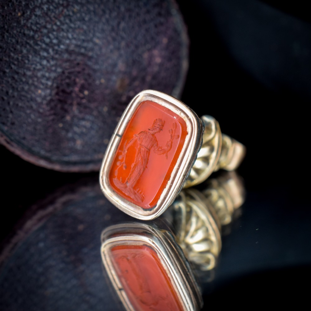An antique gold fob pendant set with a rectangular orange carnelian gemstone carved with a classical standing figure holding a branch. View V