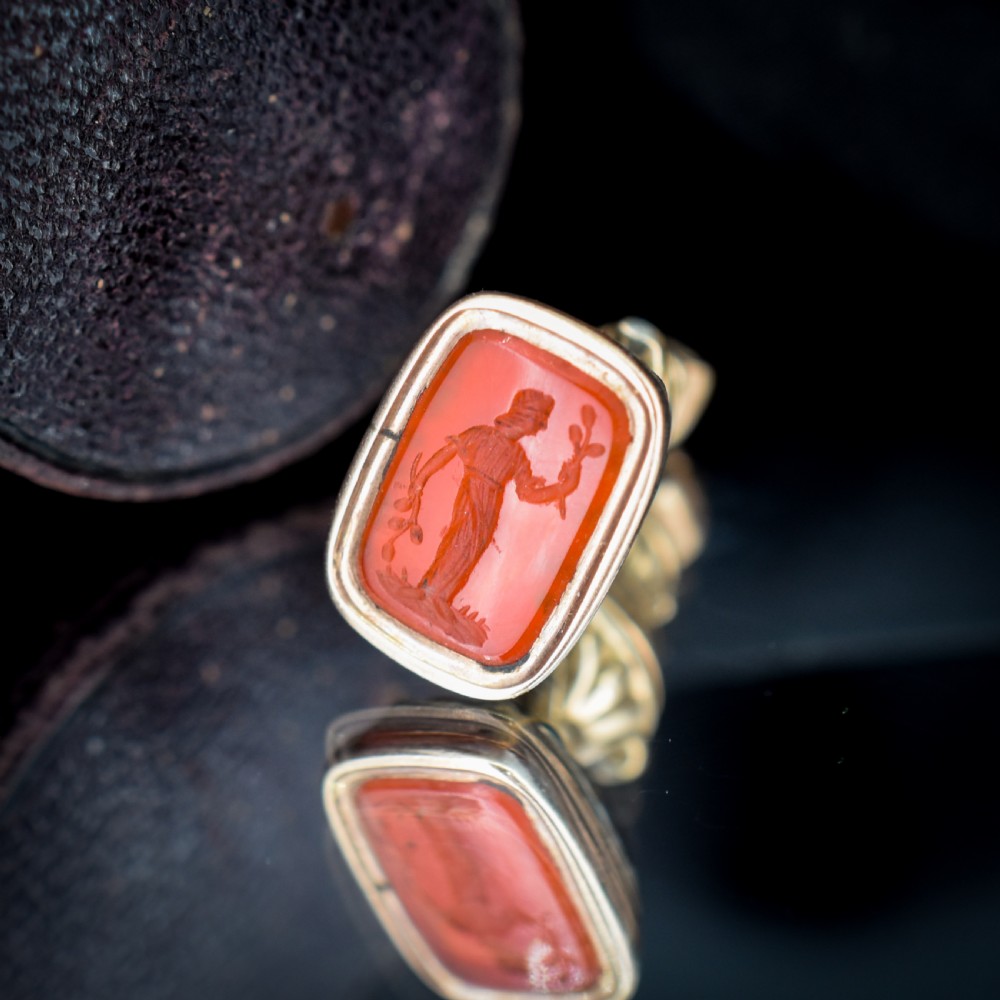 An antique gold fob pendant set with a rectangular orange carnelian gemstone carved with a classical standing figure holding a branch. View VIII