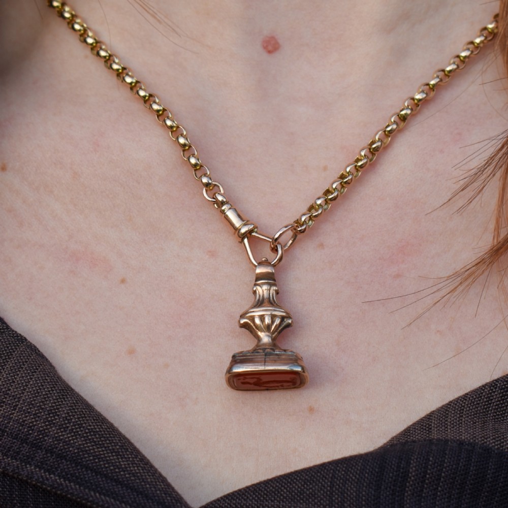 An antique gold fob pendant set with a rectangular orange carnelian gemstone carved with a classical standing figure holding a branch. View X
