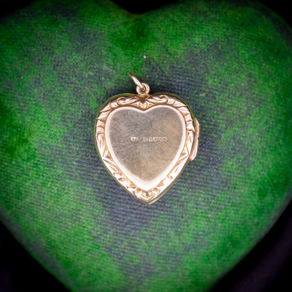 A vintage 9ct yellow gold heart-shaped locket pendant featuring engraved botanical scrollwork and a decorative scrolled border. View IV