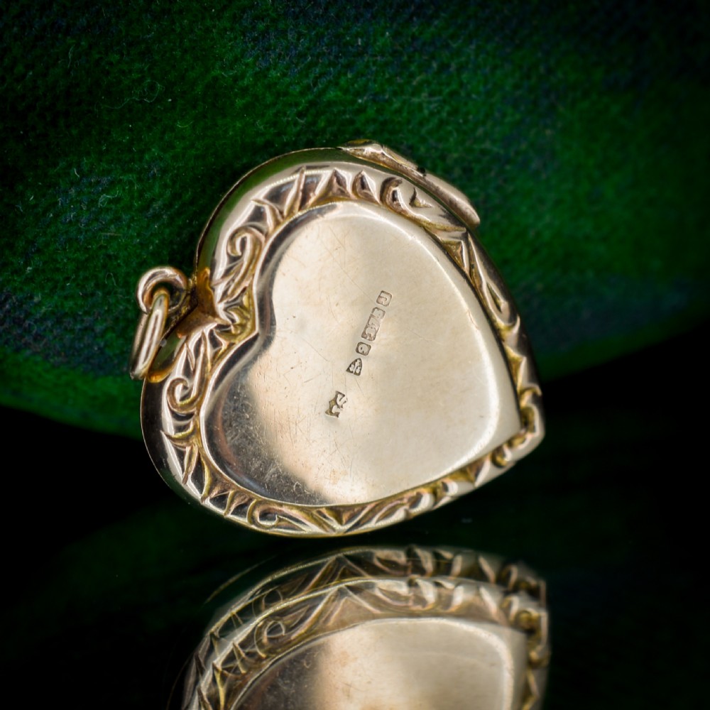 A vintage 9ct yellow gold heart-shaped locket pendant featuring engraved botanical scrollwork and a decorative scrolled border. View VIII
