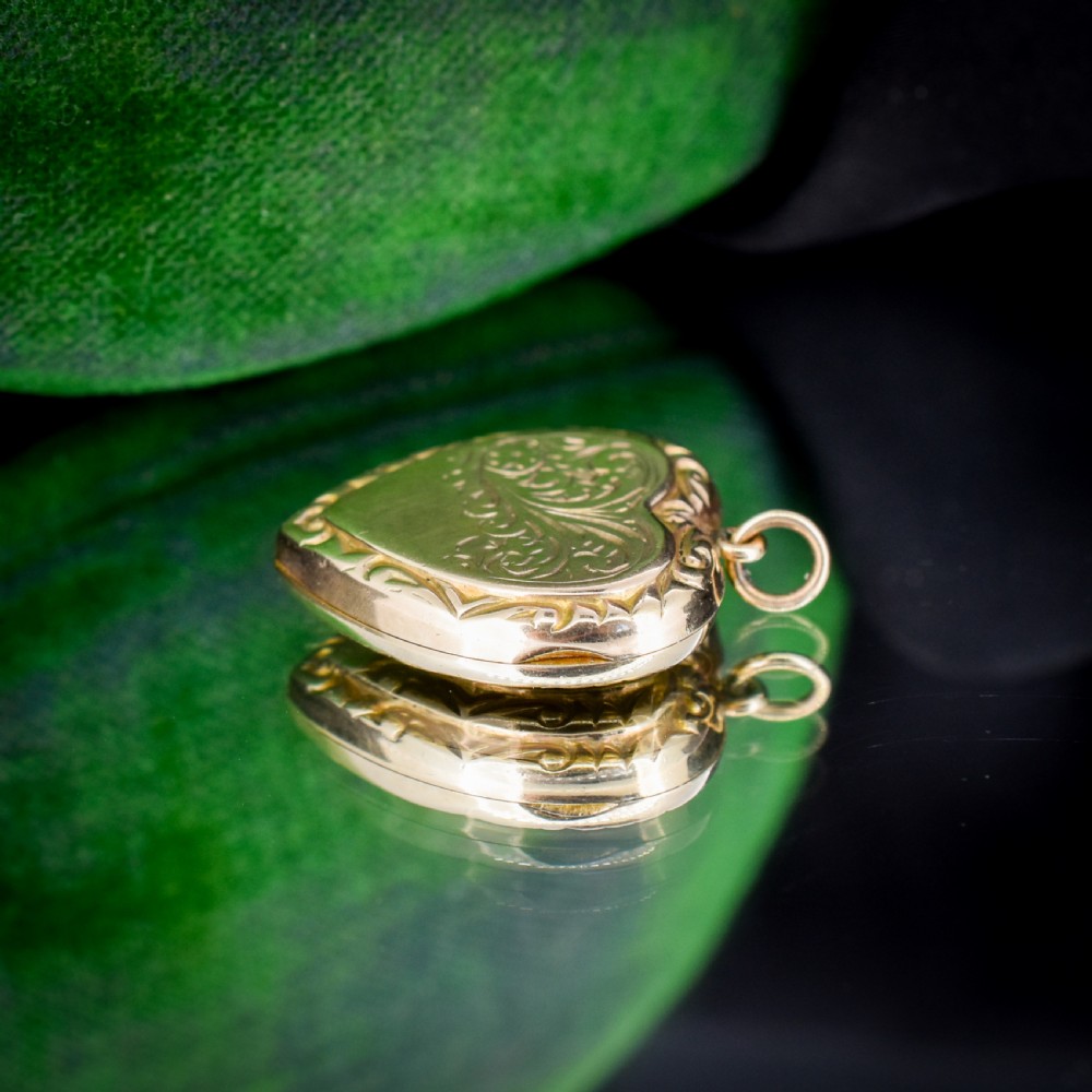 A vintage 9ct yellow gold heart-shaped locket pendant featuring engraved botanical scrollwork and a decorative scrolled border. View IX