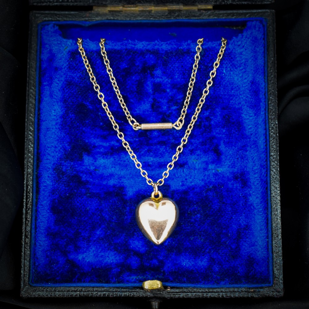 An antique 9ct yellow gold chain necklace with a smooth puffed heart pendant.