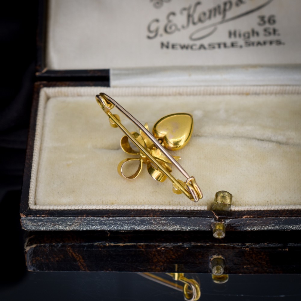 An antique yellow gold bar brooch featuring a central bow motif with a seed pearl, a dangling gold heart set with a turquoise cabochon, and two flanking turquoise stones. View VII