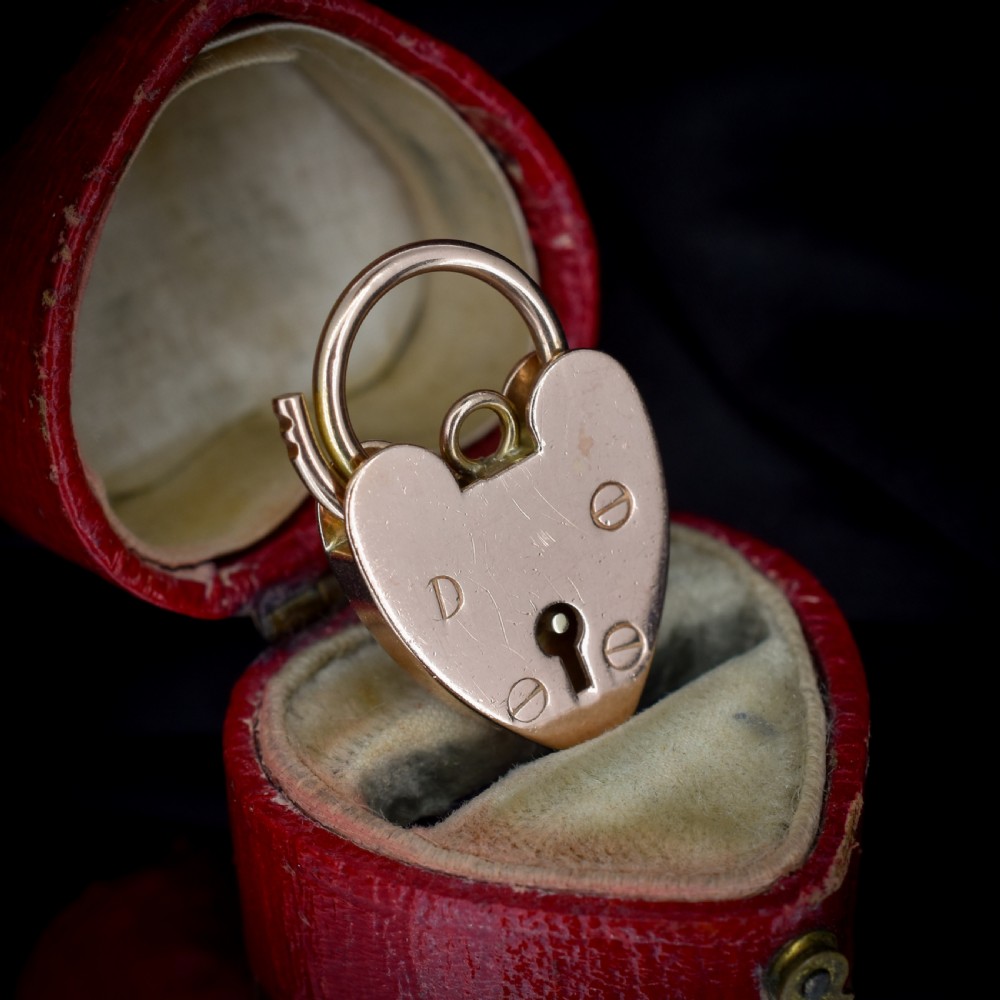 A 9ct rose gold heart-shaped padlock pendant featuring a hinged top shackle, central keyhole detail, and screw motif engravings. View IV