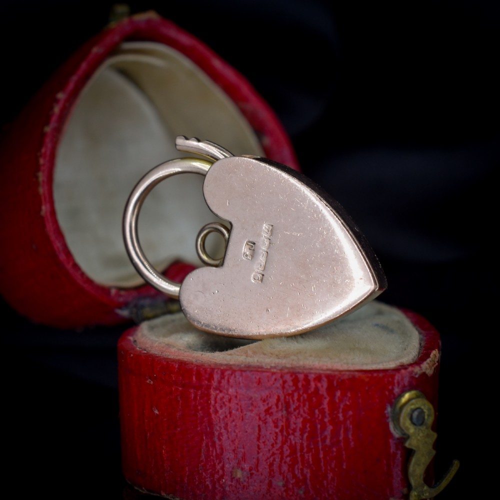 A 9ct rose gold heart-shaped padlock pendant featuring a hinged top shackle, central keyhole detail, and screw motif engravings. View VII