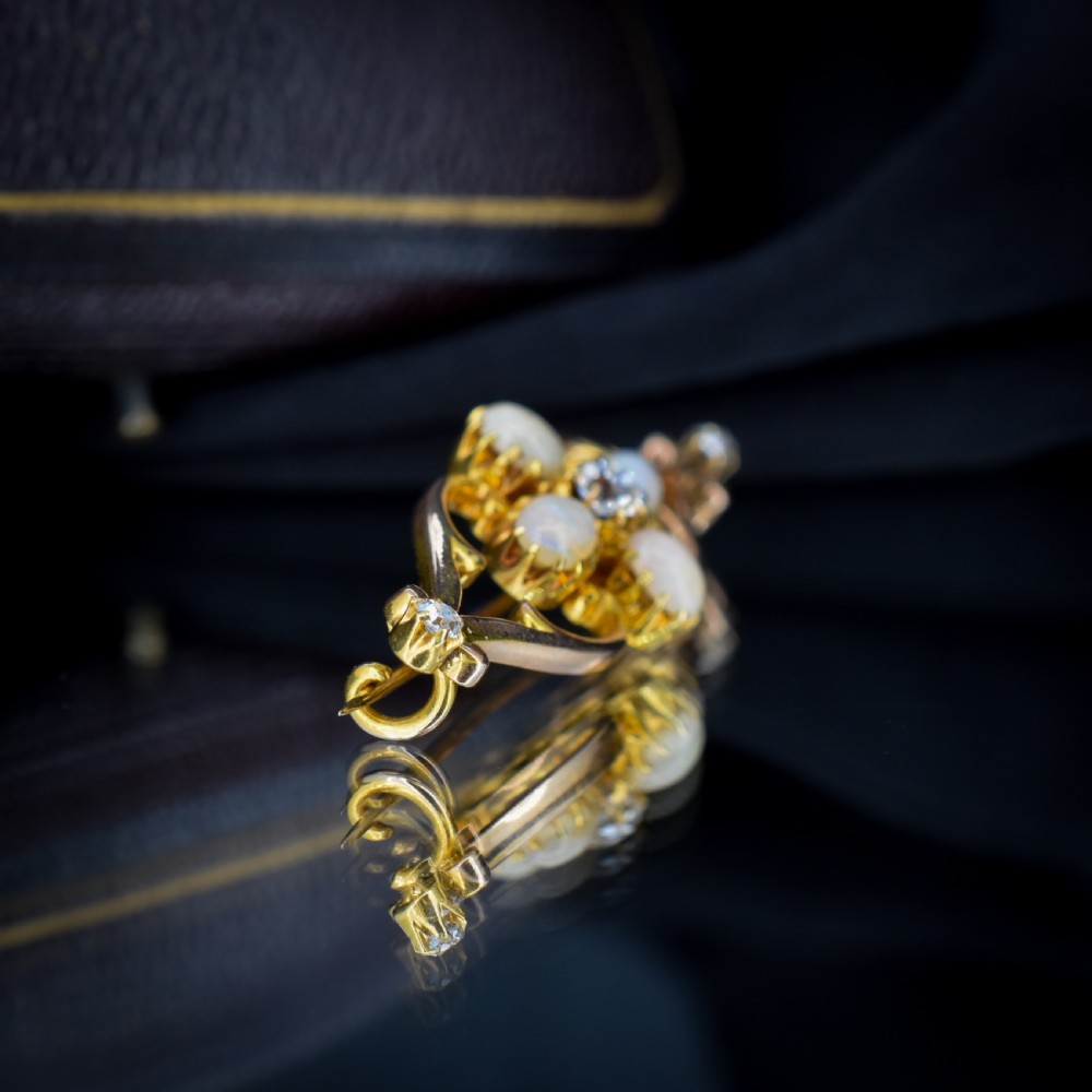 An antique 15ct gold brooch featuring four cabochon opals and central diamond accents set in an openwork scroll framing, contained inside a navy velvet presentation box. View VIII