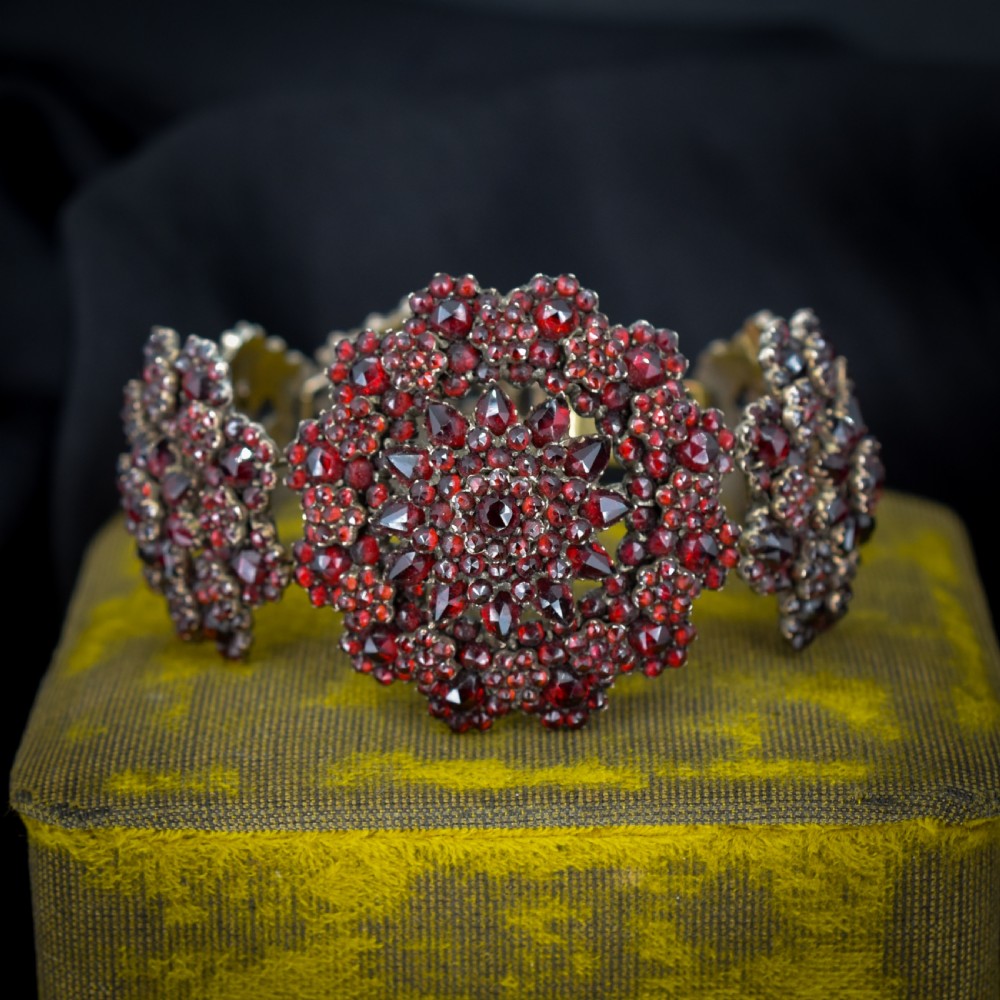 An antique Victorian Bohemian garnet bracelet featuring a central starburst cluster of rose-cut deep red garnets mounted on a wide hinged band. View III