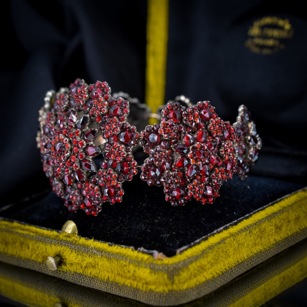 An antique Victorian Bohemian garnet bracelet featuring a central starburst cluster of rose-cut deep red garnets mounted on a wide hinged band. View IV