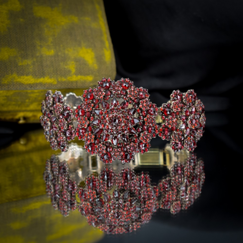 An antique Victorian Bohemian garnet bracelet featuring a central starburst cluster of rose-cut deep red garnets mounted on a wide hinged band. View VII
