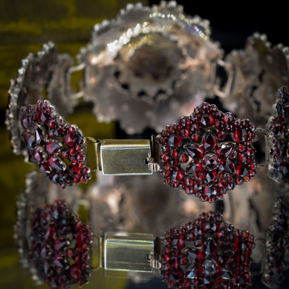 An antique Victorian Bohemian garnet bracelet featuring a central starburst cluster of rose-cut deep red garnets mounted on a wide hinged band. View VIII