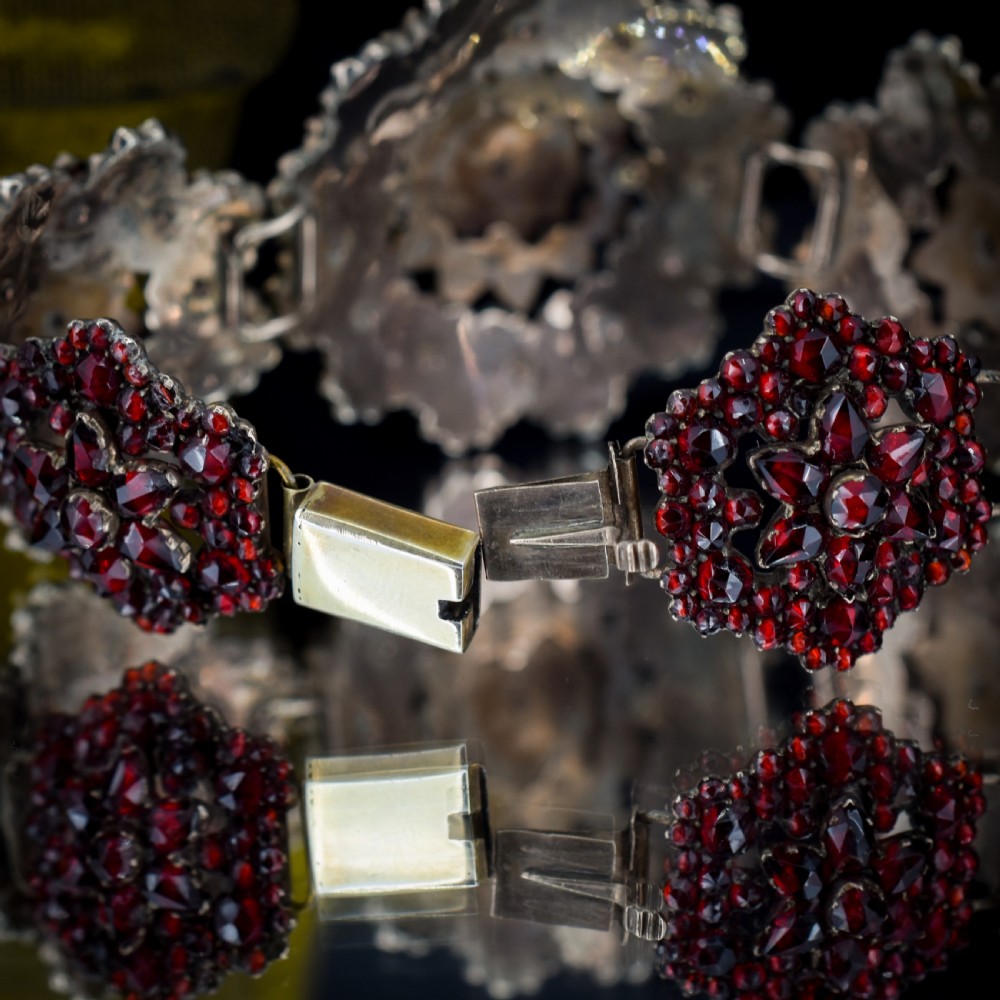 An antique Victorian Bohemian garnet bracelet featuring a central starburst cluster of rose-cut deep red garnets mounted on a wide hinged band. View X
