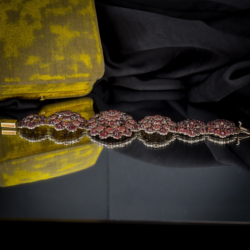 An antique Victorian Bohemian garnet bracelet featuring a central starburst cluster of rose-cut deep red garnets mounted on a wide hinged band. View XI