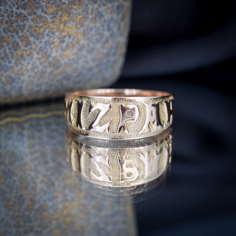 A wide 9ct gold band ring featuring the relief lettering MIZPAH set against a stippled textured background. View IV