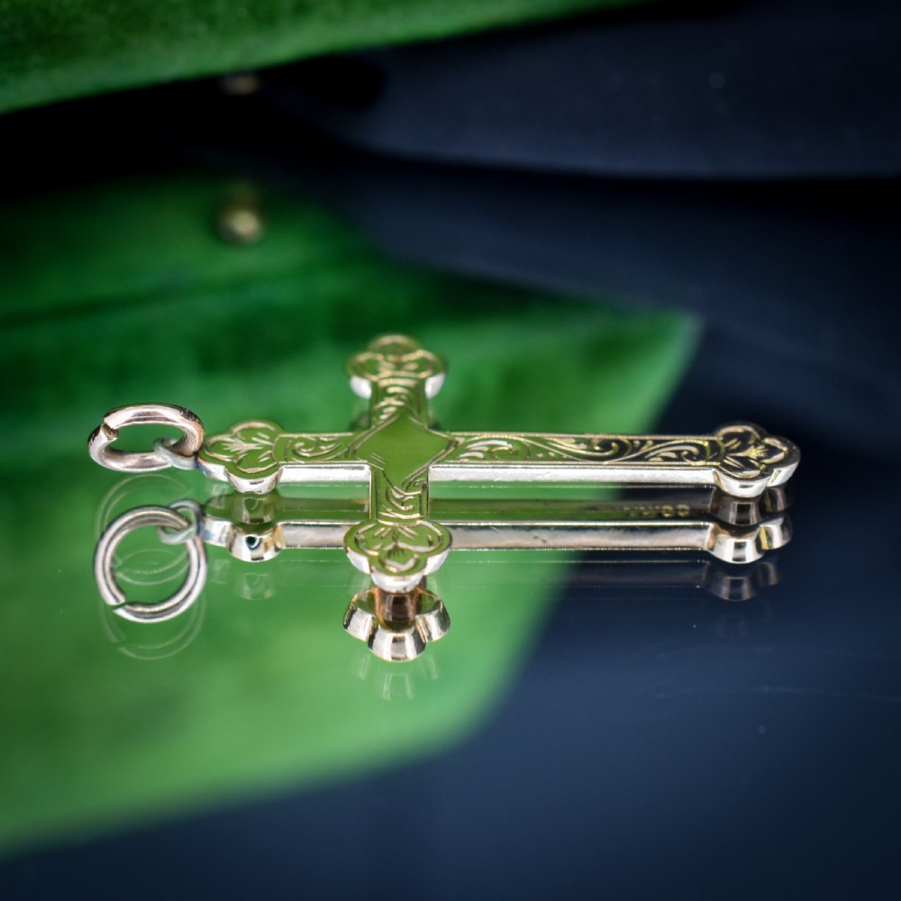 An Edwardian 9ct yellow gold cross pendant featuring hand-engraved foliate scrollwork, trefoil ends, and a circular top jump ring. View IX