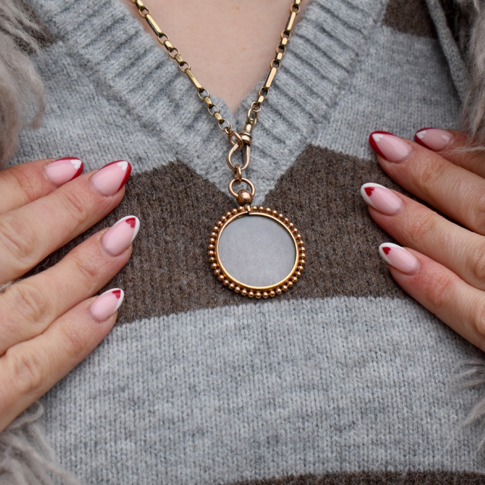 A circular antique gold locket featuring clear glass panels surrounded by a beaded outer border and a top hanging loop. View III