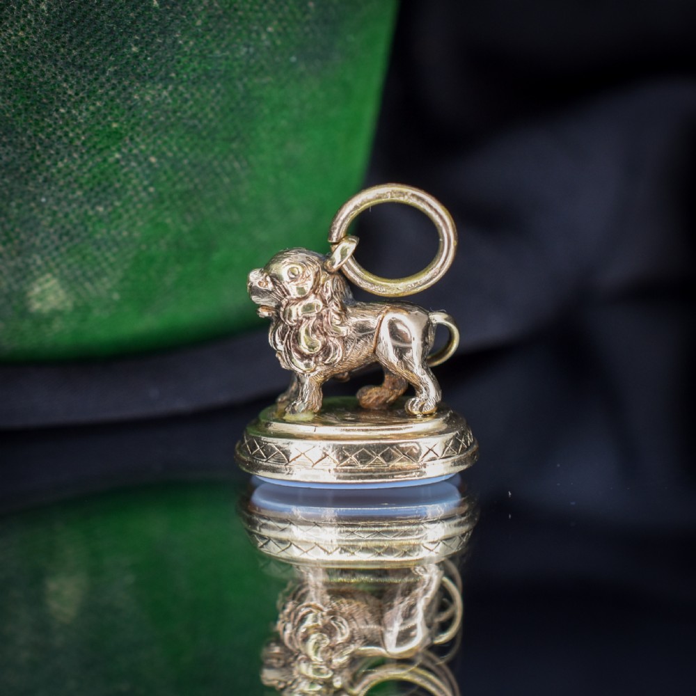 An antique gold fob seal featuring a three-dimensional standing lion figure on an engraved oval base set with a sardonyx stone. View X