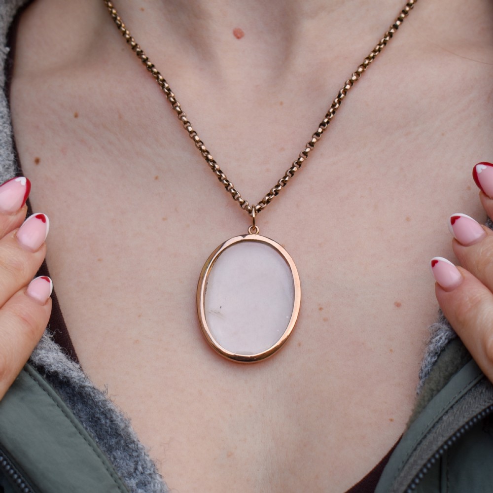 An antique oval 9ct gold photo locket featuring clear double-sided glass panels and a suspension ring set inside a velvet box. View II
