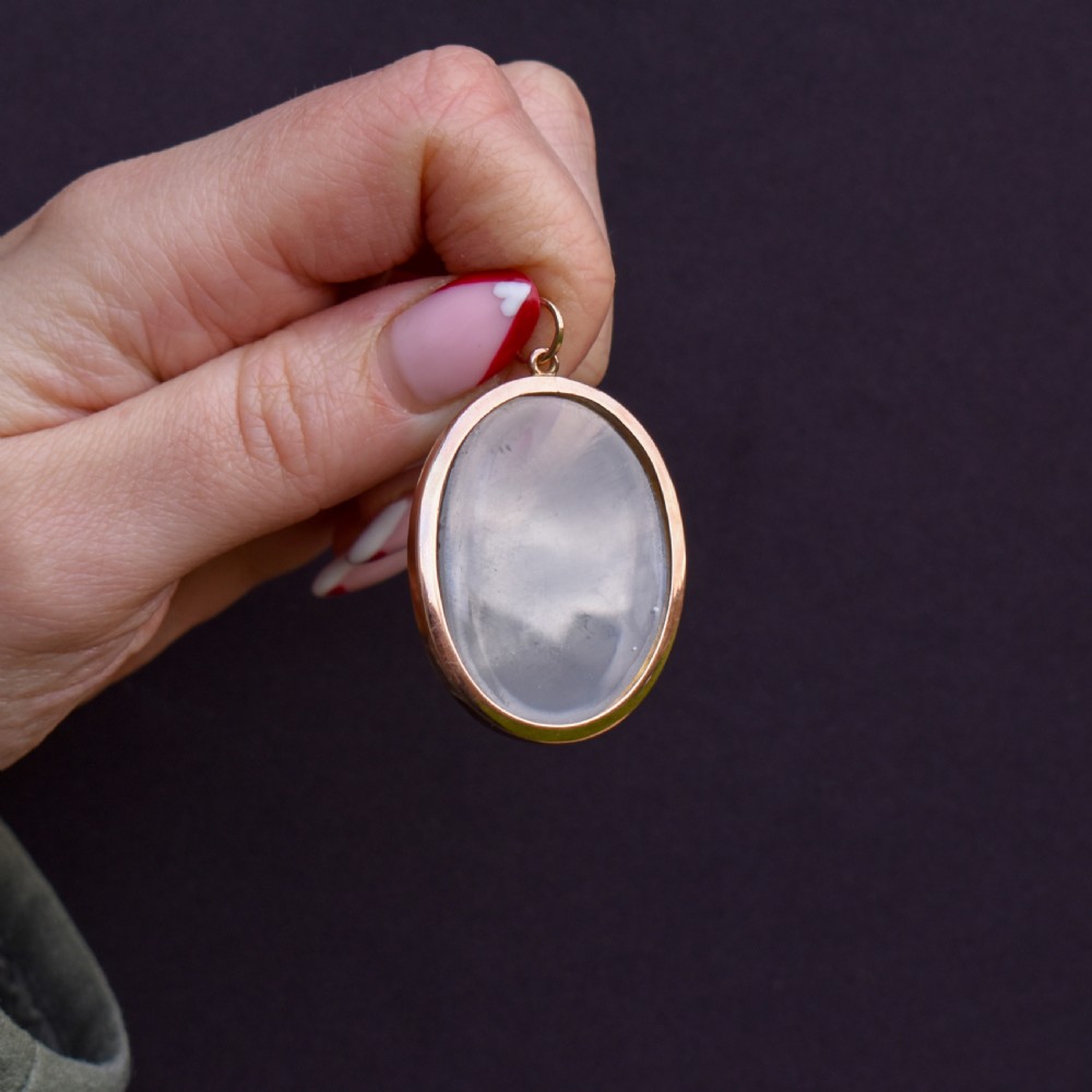 An antique oval 9ct gold photo locket featuring clear double-sided glass panels and a suspension ring set inside a velvet box. View III