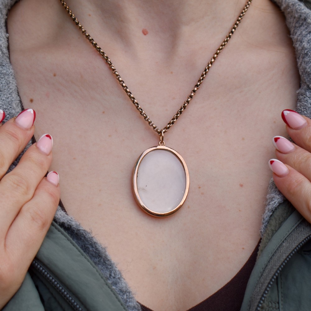 An antique oval 9ct gold photo locket featuring clear double-sided glass panels and a suspension ring set inside a velvet box. View V