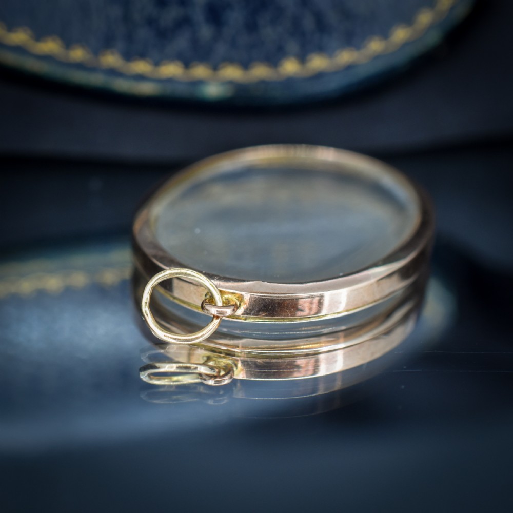 An antique oval 9ct gold photo locket featuring clear double-sided glass panels and a suspension ring set inside a velvet box. View VII