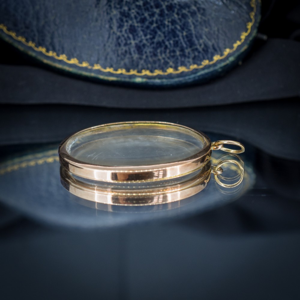An antique oval 9ct gold photo locket featuring clear double-sided glass panels and a suspension ring set inside a velvet box. View VIII