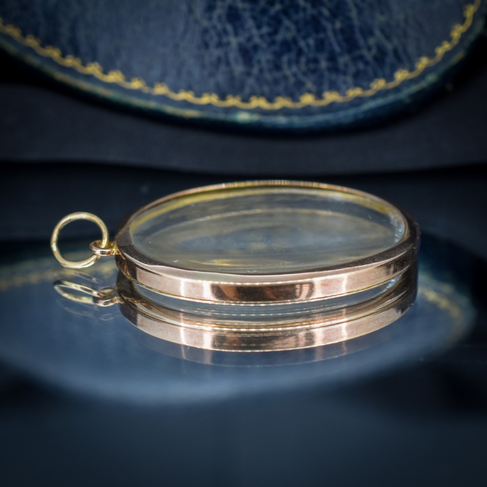 An antique oval 9ct gold photo locket featuring clear double-sided glass panels and a suspension ring set inside a velvet box. View IX