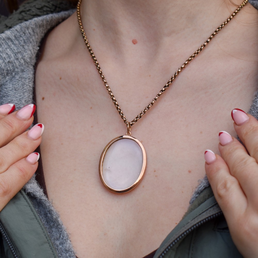 An antique oval 9ct gold photo locket featuring clear double-sided glass panels and a suspension ring set inside a velvet box. View XI