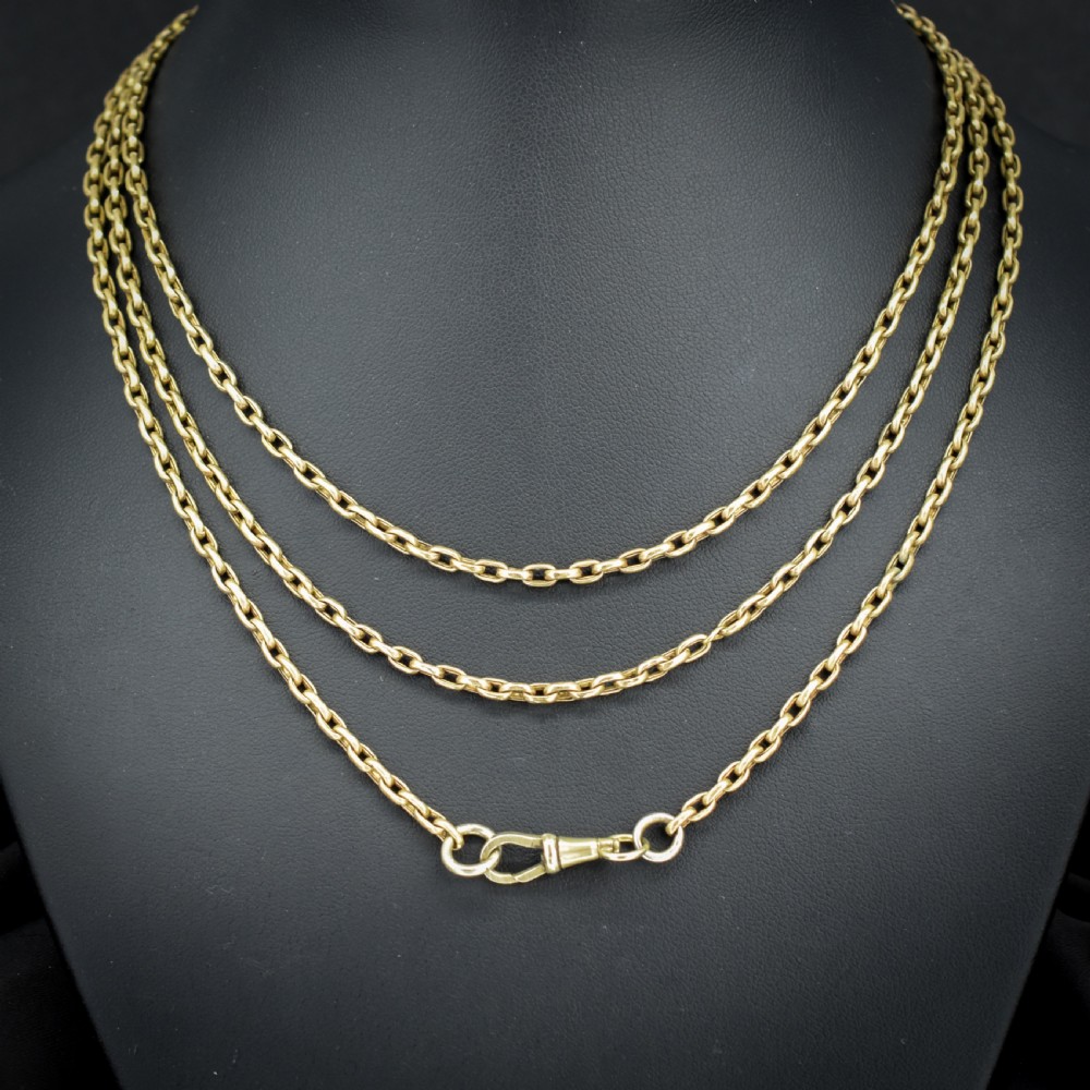 An antique rolled gold long chain with faceted belcher links arranged in loops and secured with a swivel dog clip.