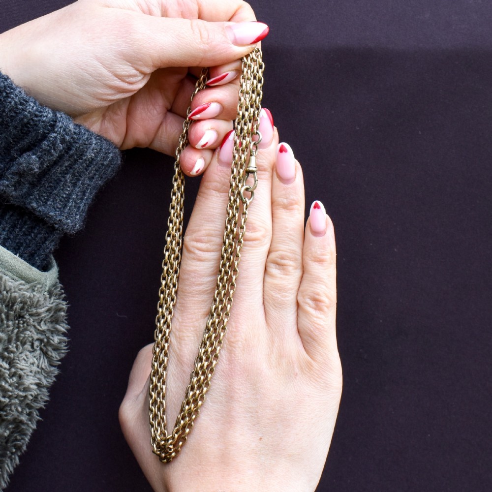 An antique rolled gold long chain with faceted belcher links arranged in loops and secured with a swivel dog clip. View II