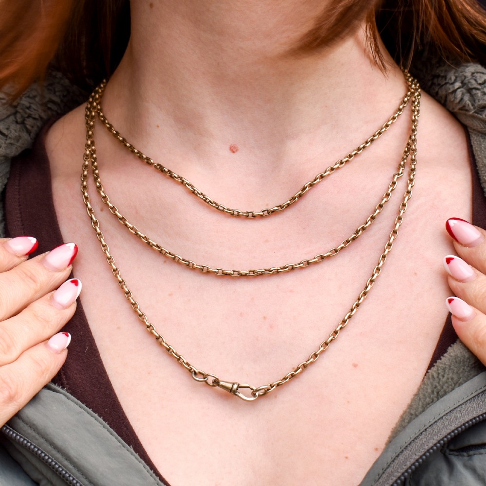 An antique rolled gold long chain with faceted belcher links arranged in loops and secured with a swivel dog clip. View IX