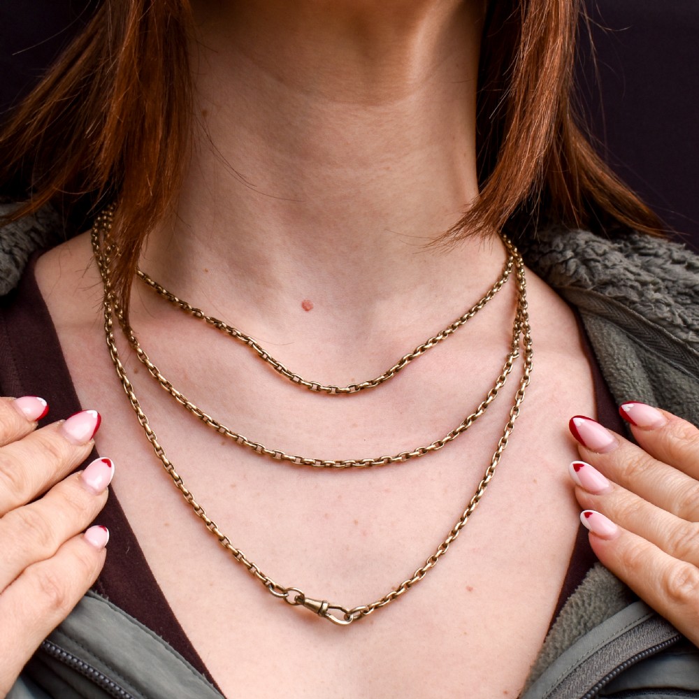 An antique rolled gold long chain with faceted belcher links arranged in loops and secured with a swivel dog clip. View X