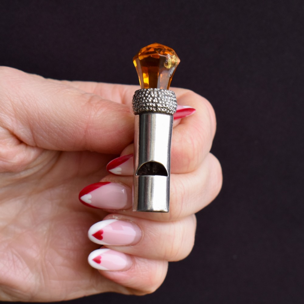 An antique sterling silver whistle pendant shaped like a thistle with a textured body and a faceted amber-coloured glass top. View II