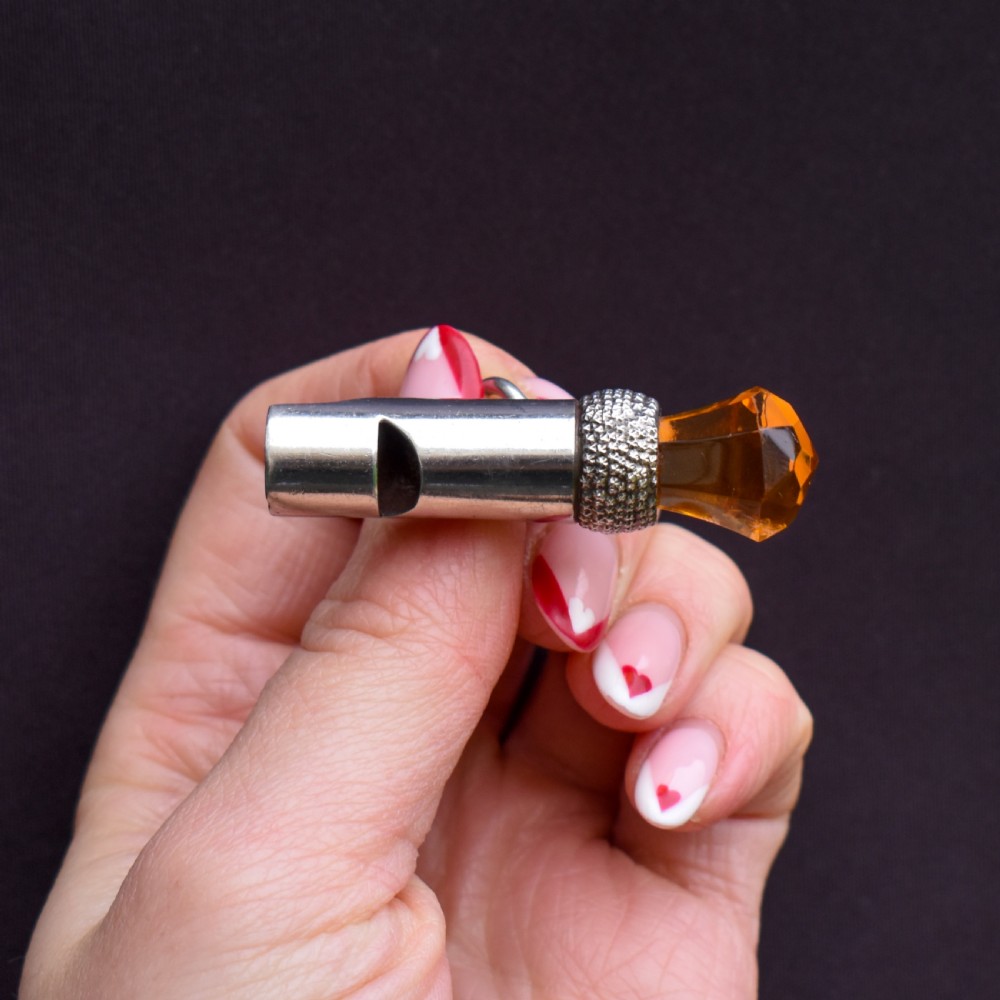 An antique sterling silver whistle pendant shaped like a thistle with a textured body and a faceted amber-coloured glass top. View III
