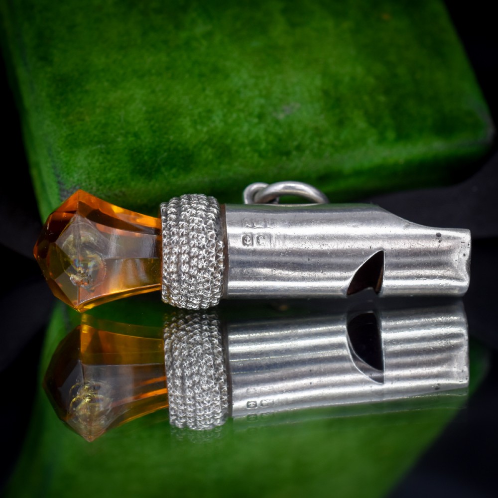 An antique sterling silver whistle pendant shaped like a thistle with a textured body and a faceted amber-coloured glass top. View VI