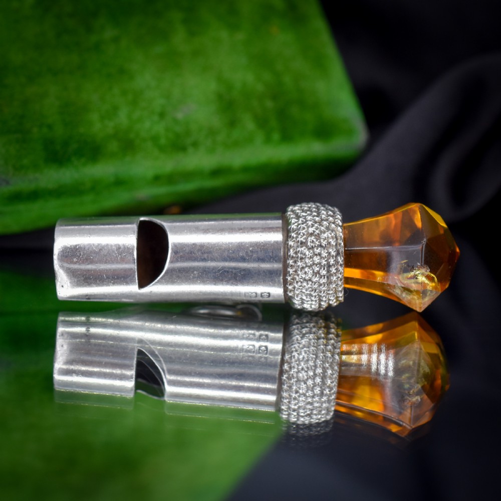 An antique sterling silver whistle pendant shaped like a thistle with a textured body and a faceted amber-coloured glass top. View IX