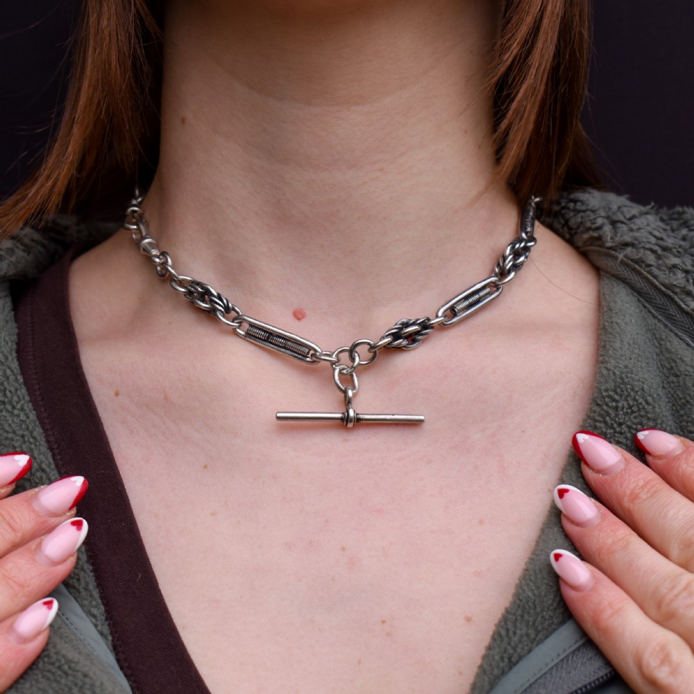 An antique sterling silver Albert chain featuring trombone links, love knot accents, a T-bar fastener, and a swivel dog clip. View II