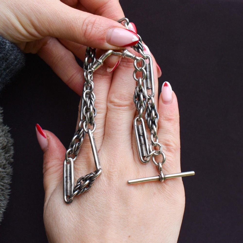 An antique sterling silver Albert chain featuring trombone links, love knot accents, a T-bar fastener, and a swivel dog clip. View III