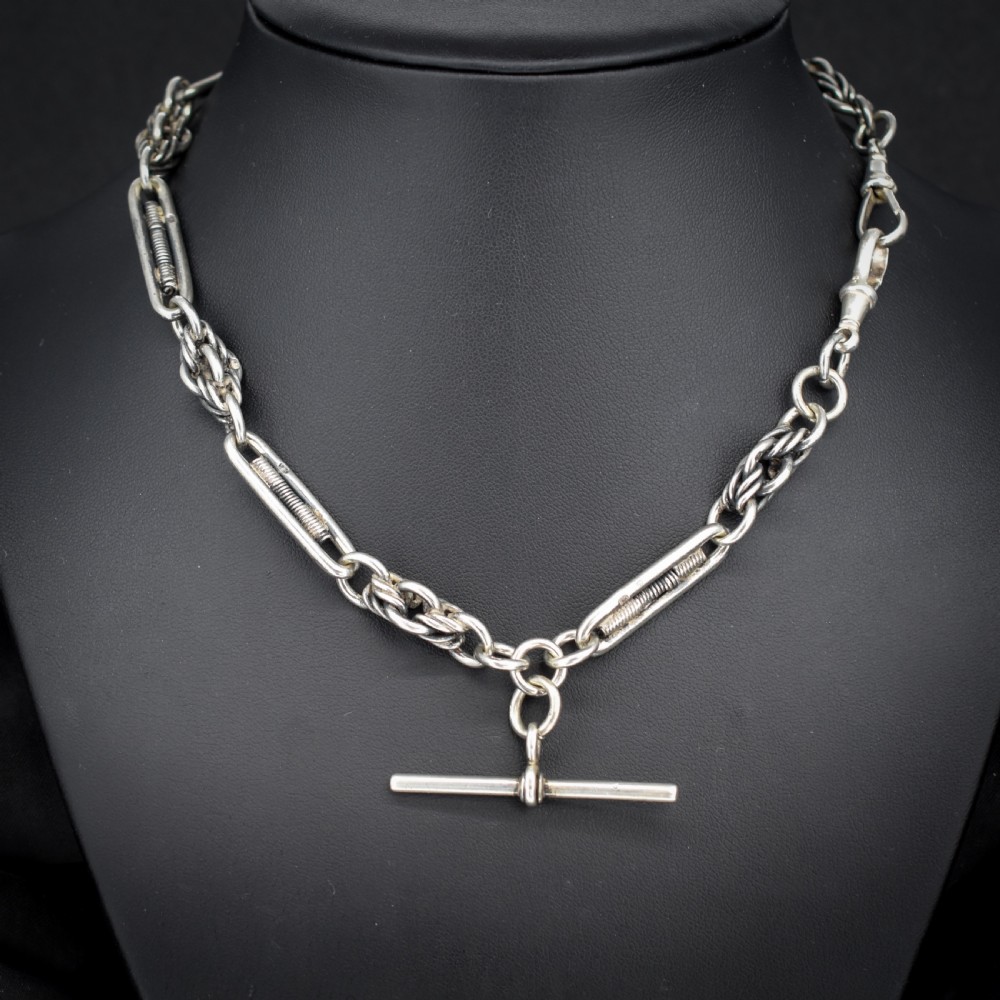 An antique sterling silver Albert chain featuring trombone links, love knot accents, a T-bar fastener, and a swivel dog clip. View IV