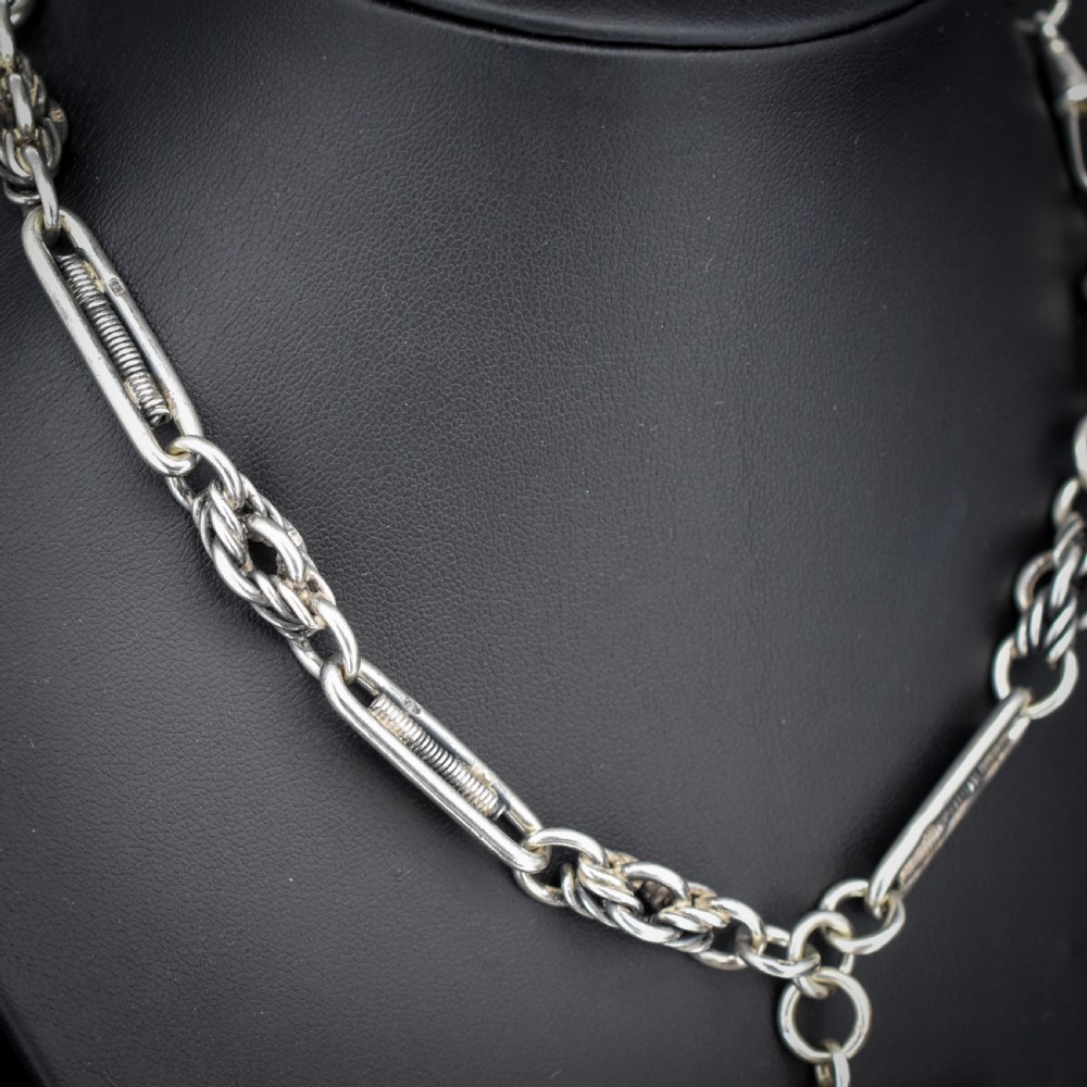 An antique sterling silver Albert chain featuring trombone links, love knot accents, a T-bar fastener, and a swivel dog clip. View VI
