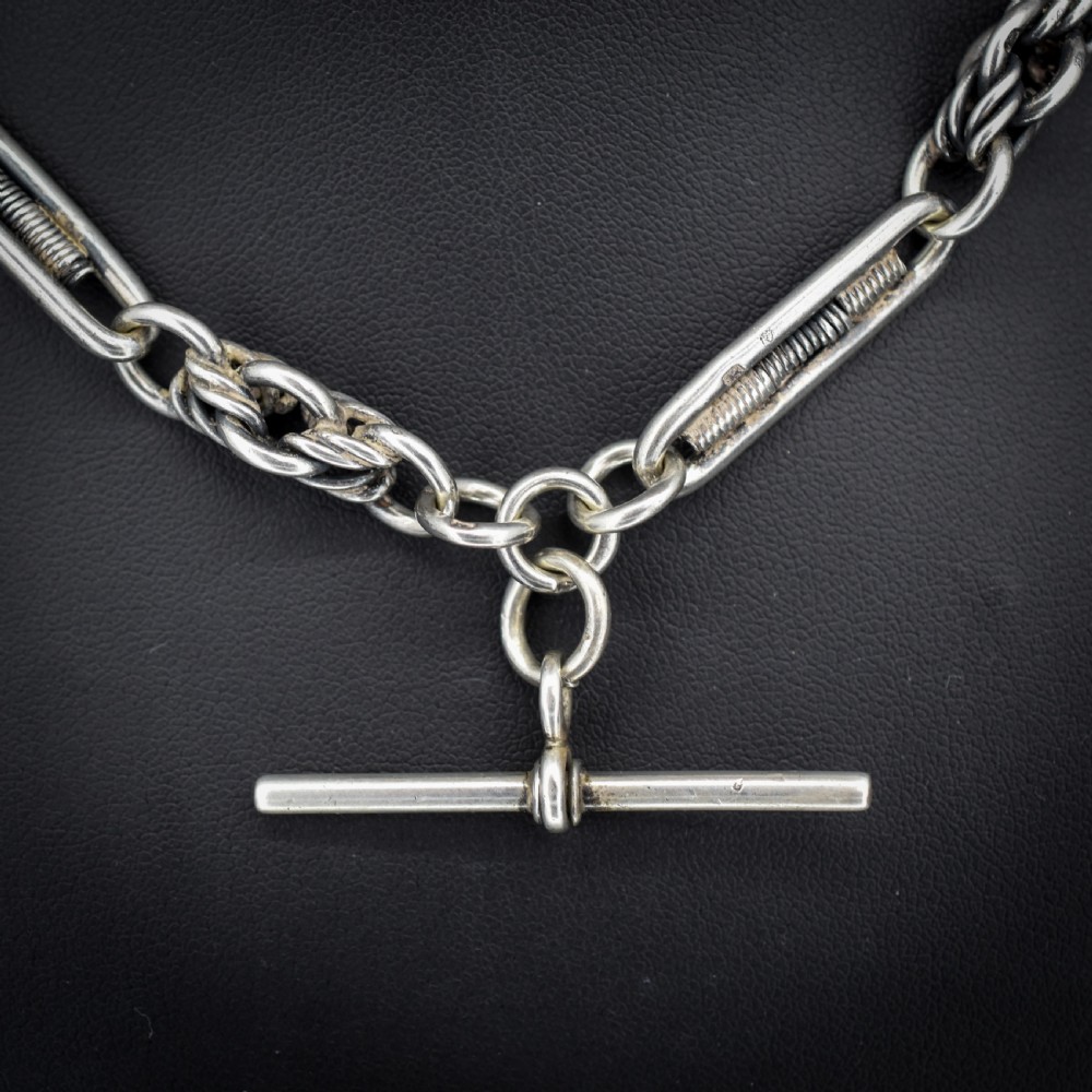 An antique sterling silver Albert chain featuring trombone links, love knot accents, a T-bar fastener, and a swivel dog clip. View VII