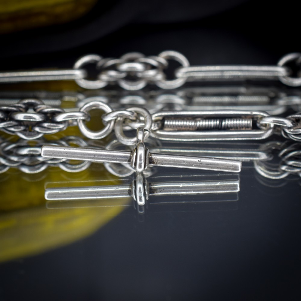 An antique sterling silver Albert chain featuring trombone links, love knot accents, a T-bar fastener, and a swivel dog clip. View IX