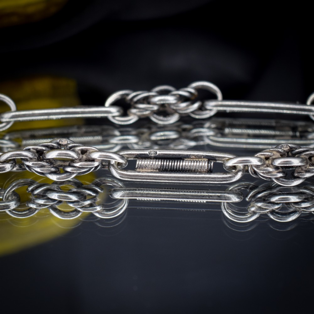 An antique sterling silver Albert chain featuring trombone links, love knot accents, a T-bar fastener, and a swivel dog clip. View X