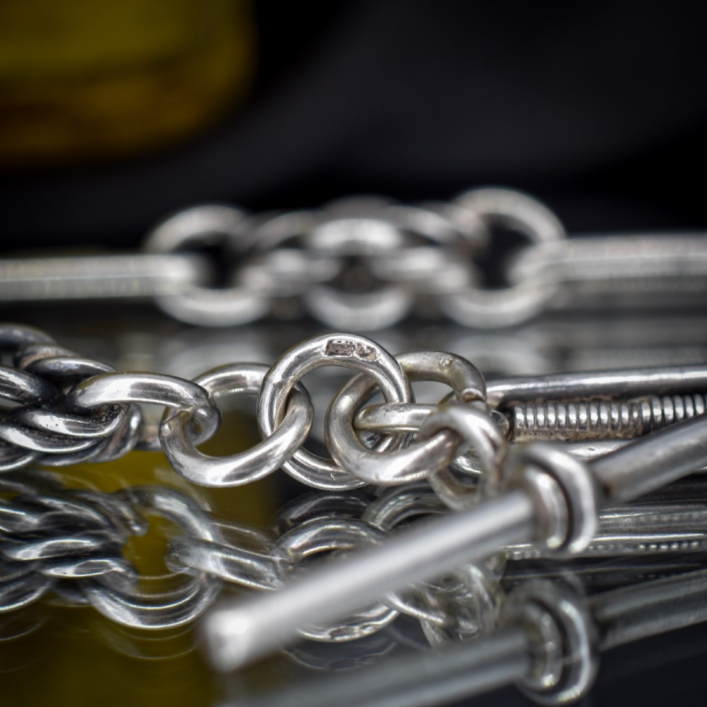 An antique sterling silver Albert chain featuring trombone links, love knot accents, a T-bar fastener, and a swivel dog clip. View XI
