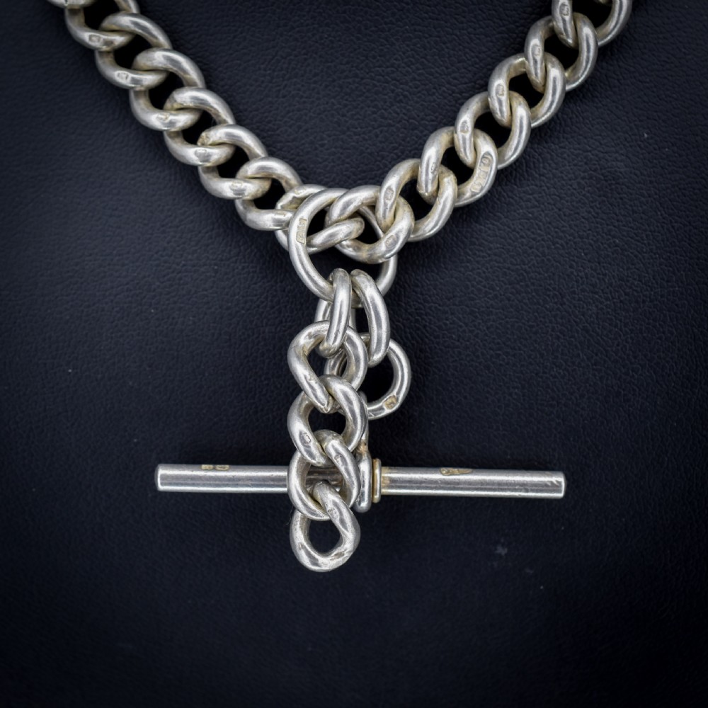 An antique sterling silver curb link Albert watch chain featuring a T-bar and dog clips displayed on blue velvet. View VI